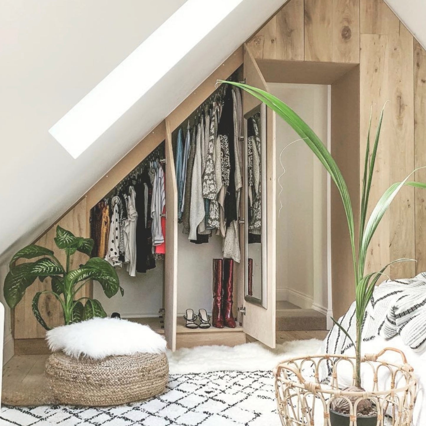 Loft bedroom with bespoke slanted ceiling wardrobes with a boho finish and decor and angled hanging rails.