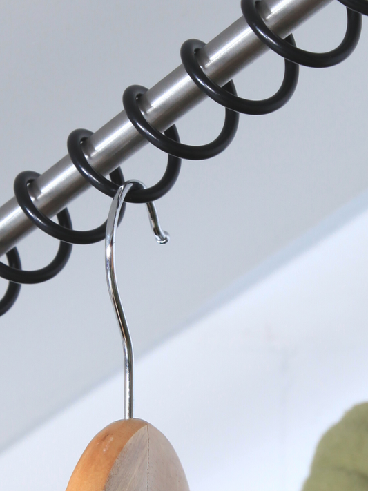 A close-up of the Zebedee Carbon Black clothes rail showing the satin finish and the metal bar with a hanger attached to it.