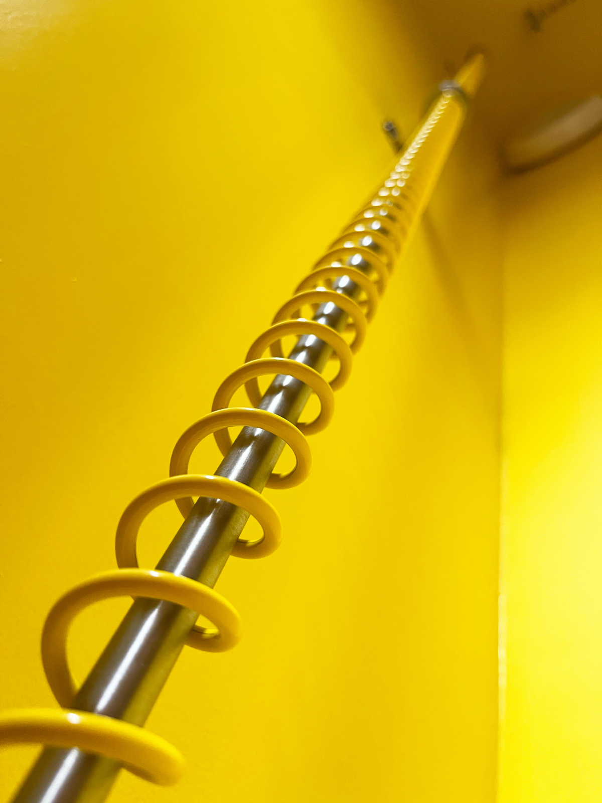 Internal view of an angled wardrobe, painted yellow and fitted with Zebedee Yellow loft wardrobe rails.