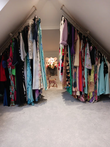 Stack of colorful folded clothes on a sloping clothes rail top fixed to an angled ceiling in a loft dressing room.