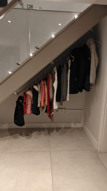 Under stair wardrobe with clothes hanging on a angled clothes rail 