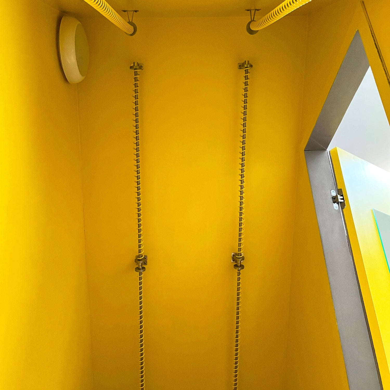 Yellow angled closet with Zebedee yellow  sloping clothes rails and a door on the right side
