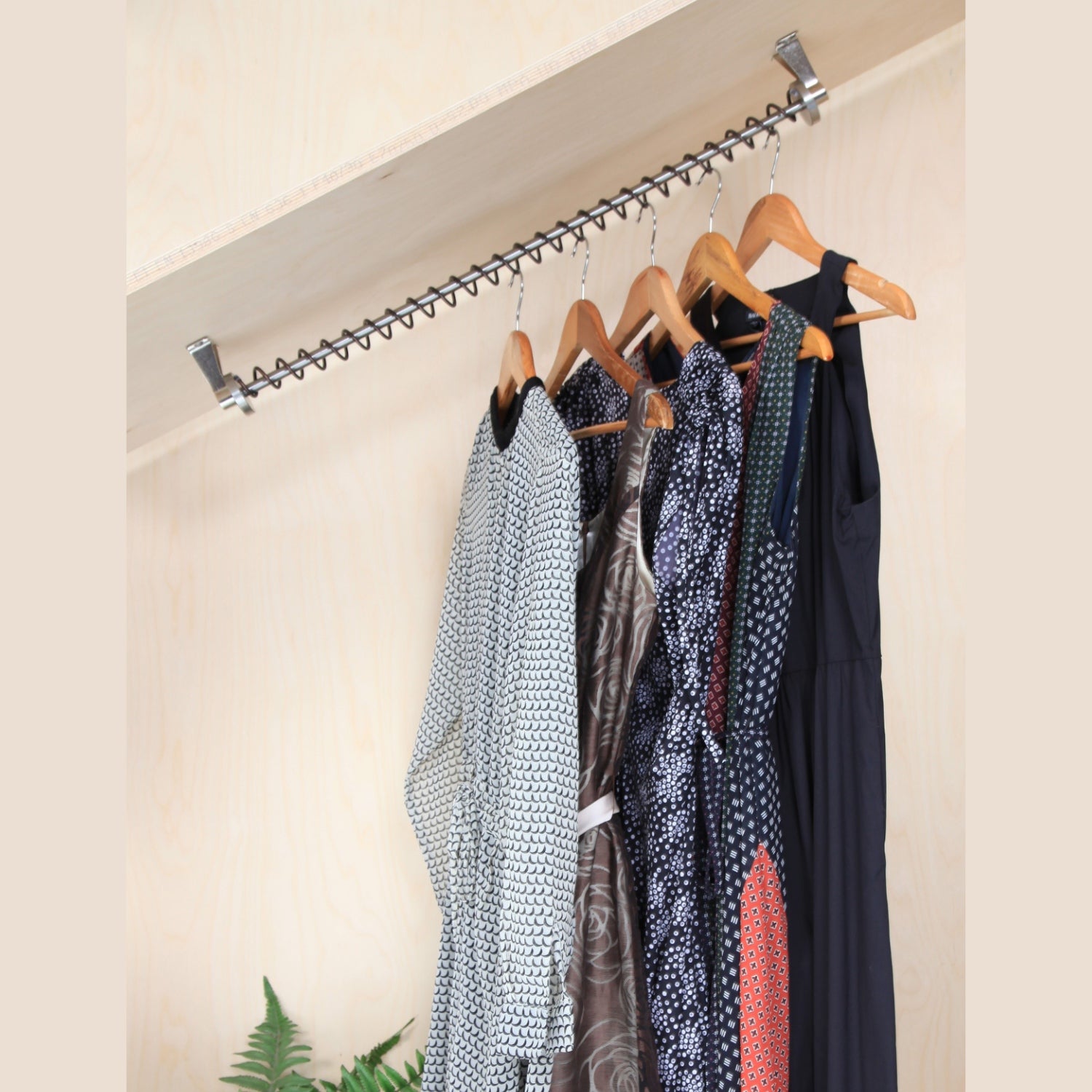 Internal view of  a wooden sloped ceiling fitted wardrobe with Zebedee Black Copper rails .