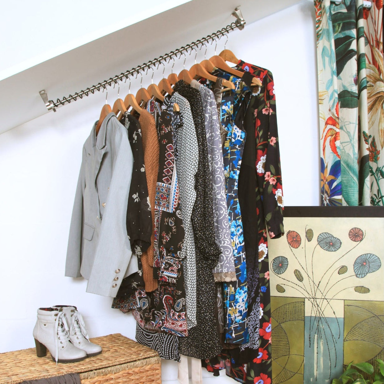 Zebedee Angled clothing rack with various garments fitted to a coombed ceiling, against a white wall, with a plant and woven basket in the foreground.