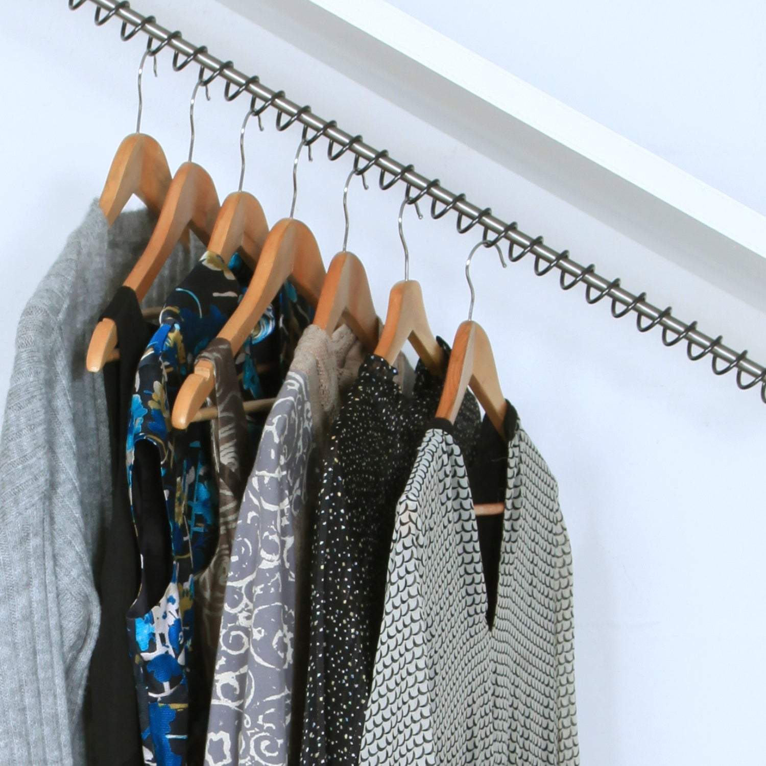 Internal view of a sloped ceiling wardrobe with a top fixed angled clothes rail, clothes hangers and clothes. 