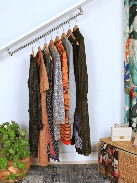 Sloped ceiling clothes rail set into a under stairs alcove with clothes basket and plants