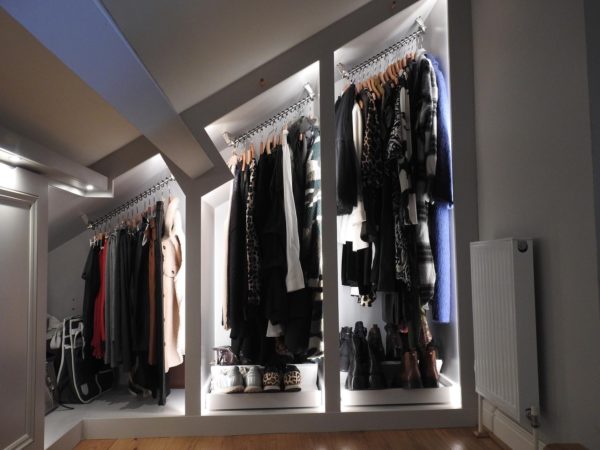 3 angled clothing rails fitted into 3 different sized recesses in a wall, all with sloped ceilings and clothing hanging from them.