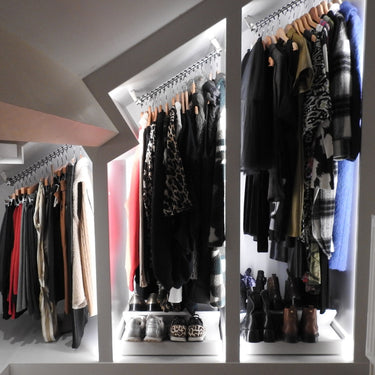 bespoke sloped closet with angled hanging rails and clothes hanging  on hangers