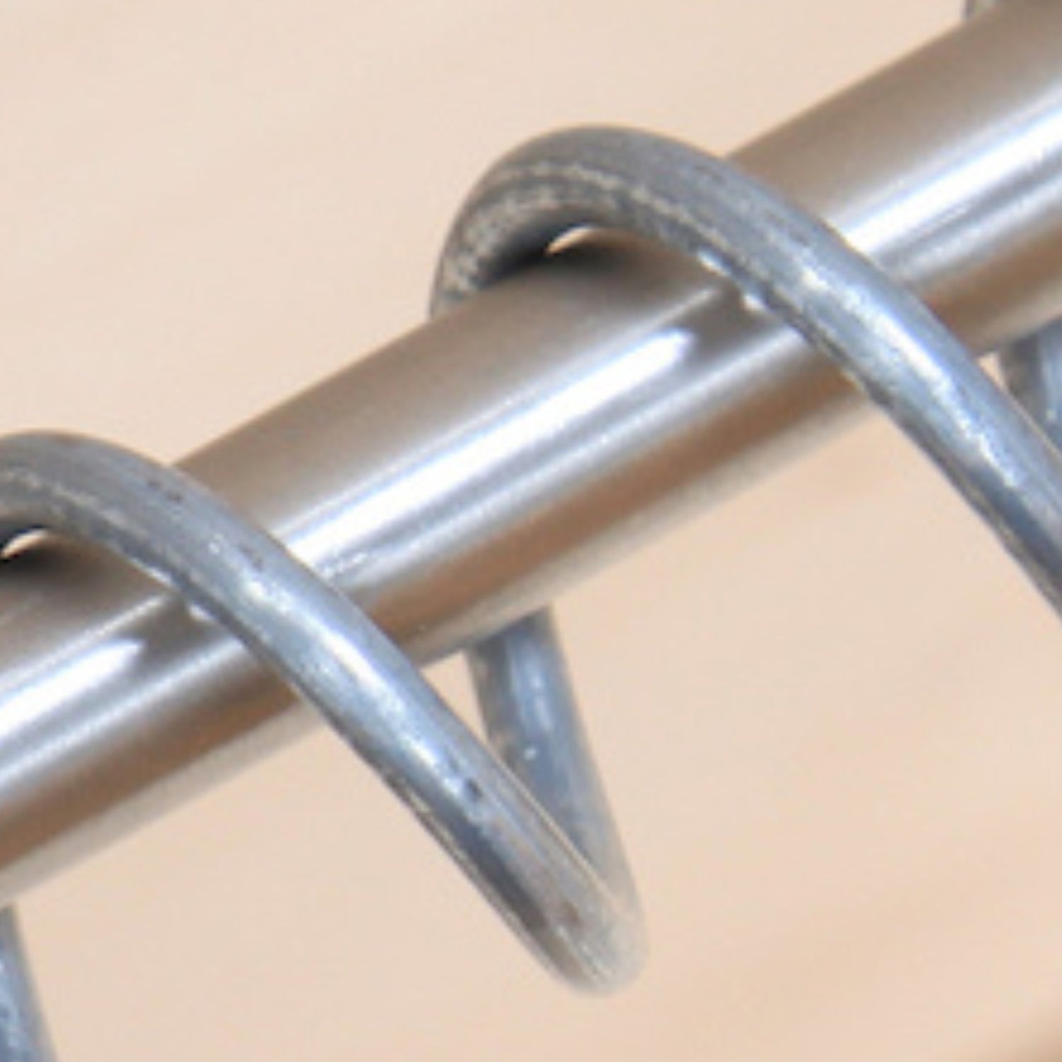 Close up of Zebedee hanging rail stainless steel rod and coil on a beige background