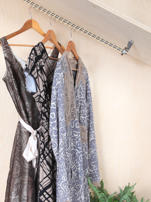 A slanted clothes rail top mounted in an angled alcove with coat hangers and clothes following the slant of the ceiling.