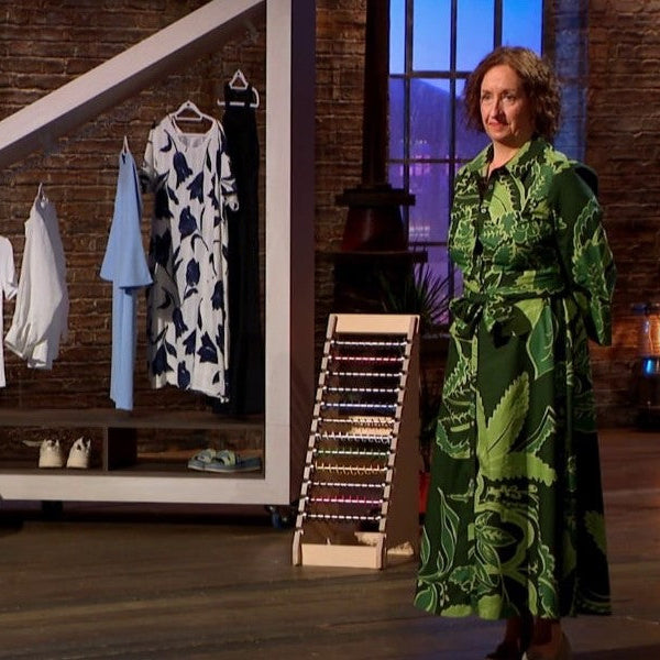 Zebedee designer Diane Challender in a green patterned dress standing in BBC Dragons' Den with Zebedee angled display stand and decor.